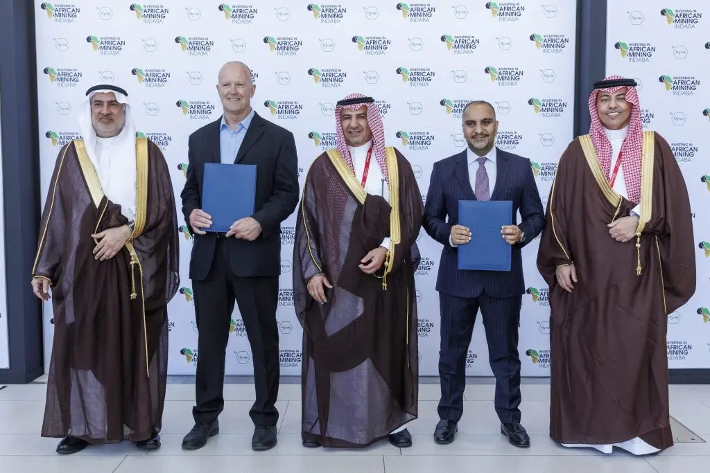 Master Drilling International and AlRushaid Group representatives holding the signed joint venture agreement in front of the Investing in African Mining Indaba backdrop.